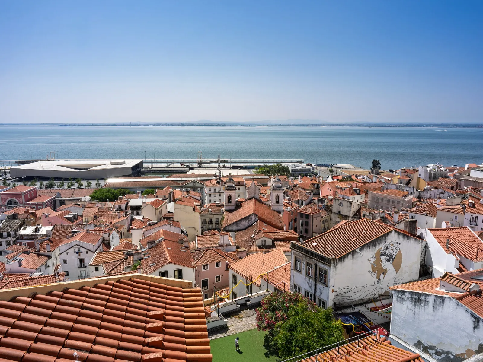 Red-tiled rooftops of Lisbon's Alfama district sloping down to the Tagus River and the cruise terminal
